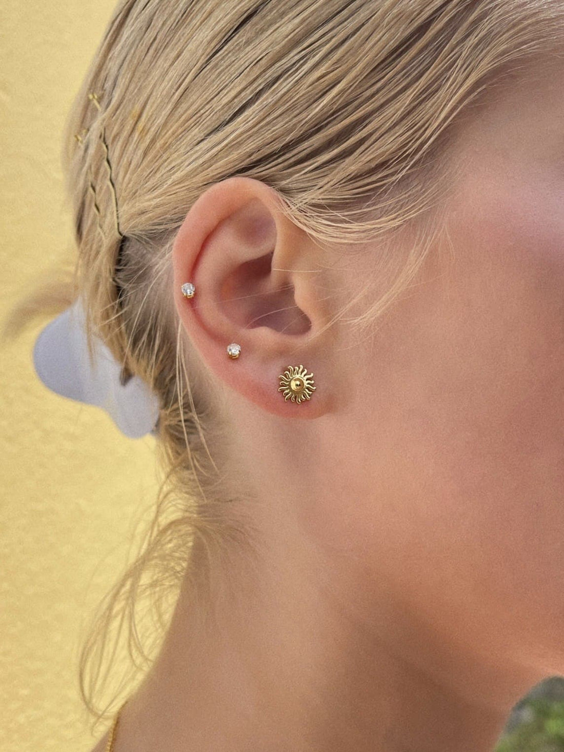 Et par Pallantis Smykker Vivian Sol Ørestikker i forgyldt sølv med solformede ørestikker med bølgede stråler og en poleret glans, vist på en hvid baggrund.